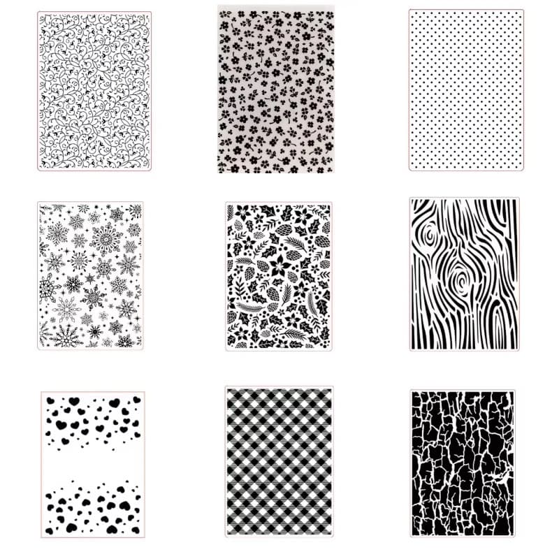 Neuf classeurs de gaufrage présentés sur fond blanc, avec des motifs de flocons, de houx, de veinage de bois, de carreaux, de craquelé, de cœurs, de pois, de fleurs et d'arabesques.