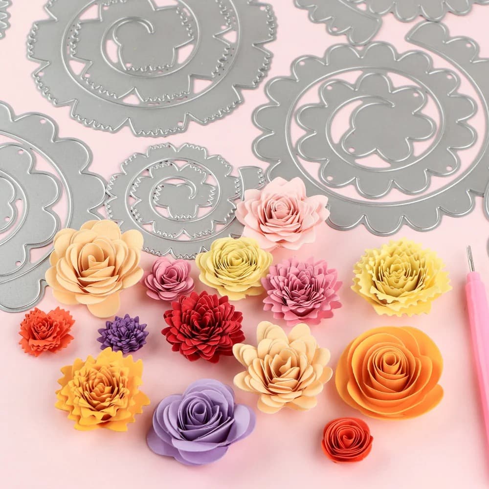 Matrices en spirale posées sur un fond rose, entourées de roses et de dahlias en papier enroulé dans une quinzaine de couleurs.