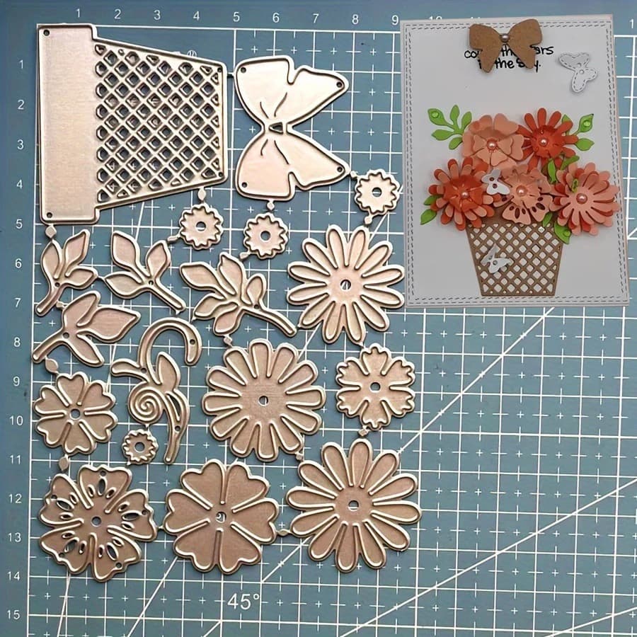 Le jeu de matrices posé sur un tapis de découpe bleu, à côté d'une carte montrant un panier tressé garni de fleurs orangées et d'un papillon.