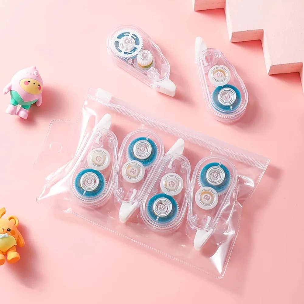Six dévidoirs de colle transparents, dont quatre rangés dans une pochette zippée, posés sur un fond rose avec deux petites figurines.