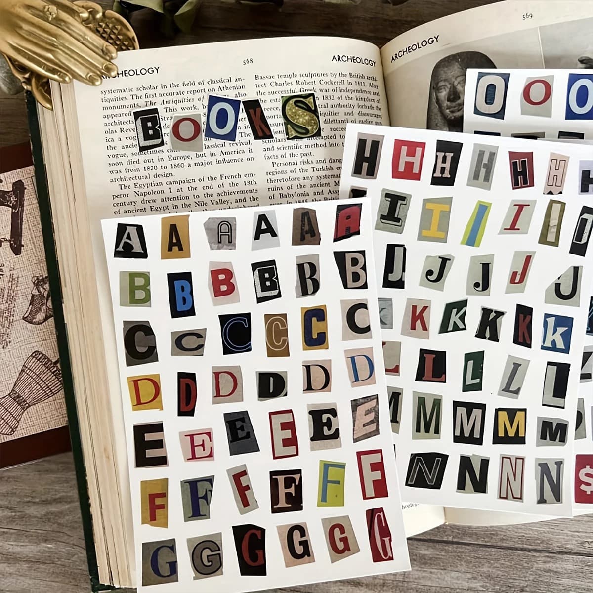 Planches de lettres découpées aux typographies variées posées sur un livre ancien ouvert, avec un mot composé sur la page.